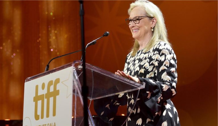 Meryl Streep standing smiling at an acrylic lectern